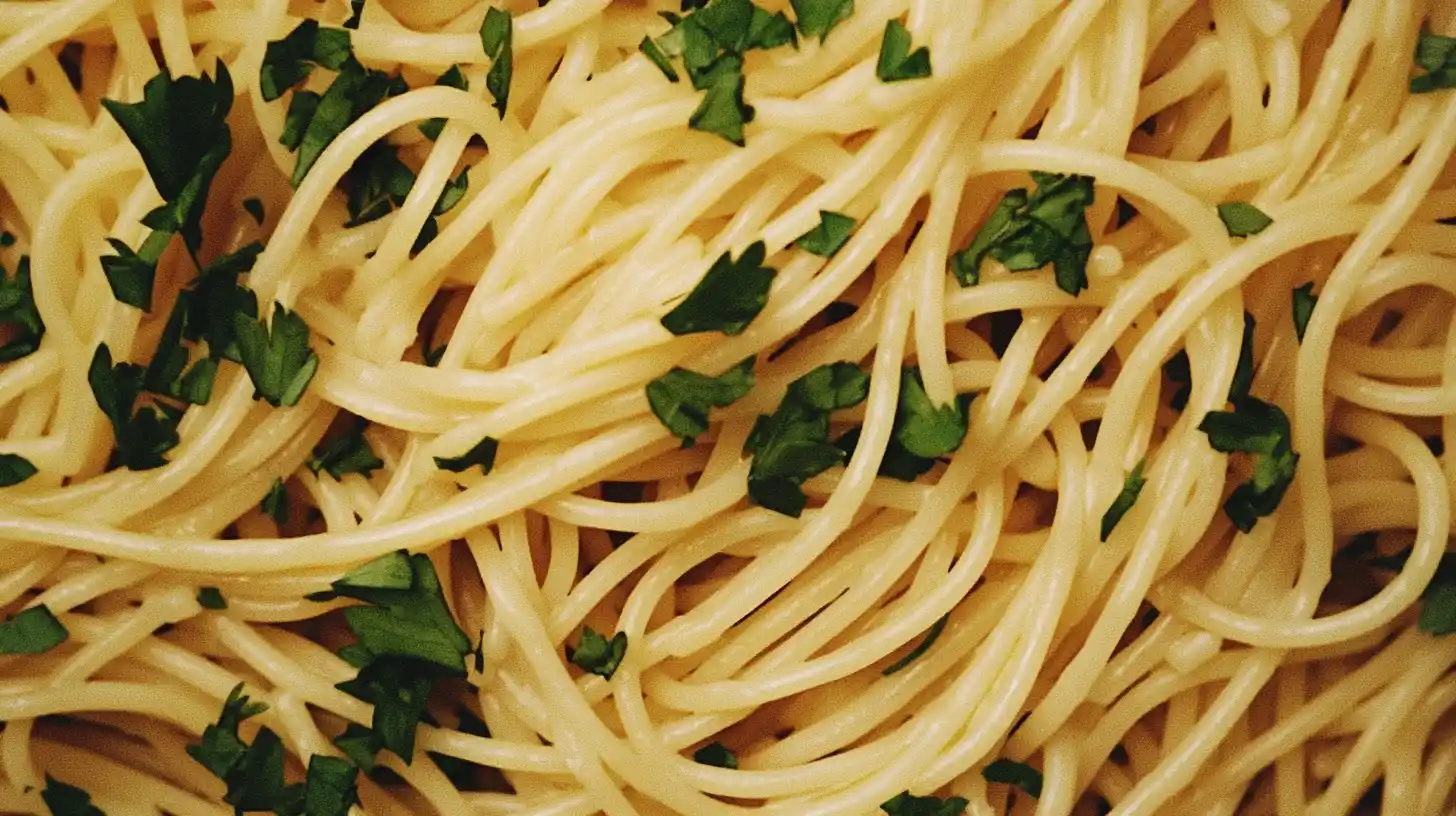 A plate of spaghettini with olive oil and parsley.